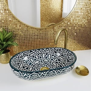 Op de afbeelding: Een ovaal keramisch badkamer wastafel met een zwart-wit geometrisch patroon. De wastafel heeft een donkergroene rand en een goudkleurige afvoer. Een gouden kraan en een klein gouden schaaltje zijn ook zichtbaar.
