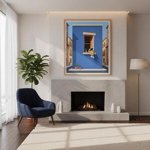 May include: A framed art print depicts a person sitting in a window against a blue wall, with buildings on either side. The artwork is displayed above a fireplace, with a blue armchair and a potted plant to the left. A floor lamp stands to the right.