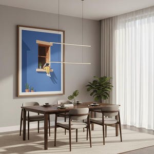 May include: A dining room scene featuring a wooden table and four chairs. A large framed artwork with a blue background hangs on the wall. Two linear pendant lights hang above the table. A rug and curtains complete the room.