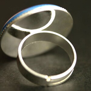 May include: A silver ring with a round, blue and white cabochon setting.