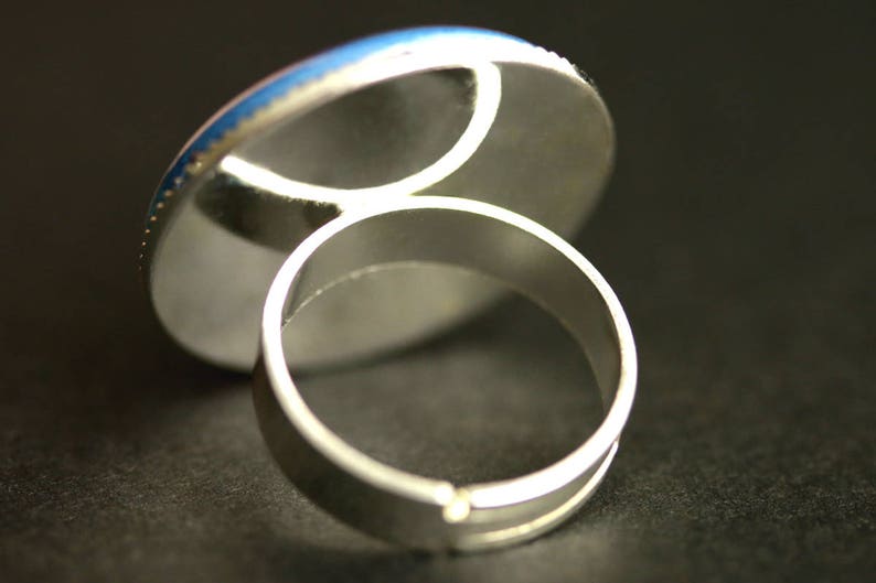 May include: A silver ring with a round, blue and white cabochon setting.