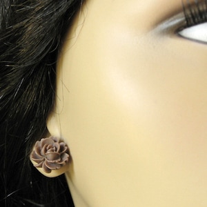 May include: A pair of brown flower-shaped earrings. The earrings are made of a smooth, matte material and have a delicate, feminine design.