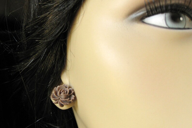 May include: A pair of brown flower-shaped earrings. The earrings are made of a smooth, matte material and have a delicate, feminine design.