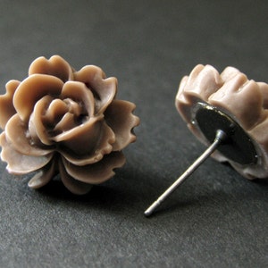 May include: A pair of brown rose-shaped stud earrings. The earrings are made of a smooth, matte material and have a simple, elegant design.