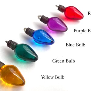 May include: Five miniature light bulbs in different colors: red, purple, blue, green, and yellow. The bulbs are arranged in a row from left to right, with the red bulb at the top and the yellow bulb at the bottom.
