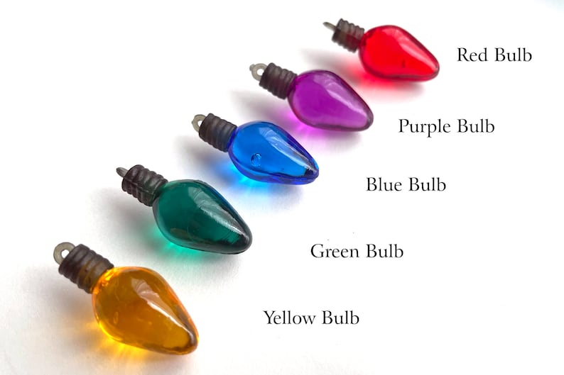 May include: Five miniature light bulbs in different colors: red, purple, blue, green, and yellow. The bulbs are arranged in a row from left to right, with the red bulb at the top and the yellow bulb at the bottom.