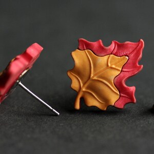 Pu&ograve; includere: Un paio di orecchini a forma di foglia rossa e gialla. Gli orecchini sono realizzati in pasta polimerica e hanno un design semplice ed elegante.