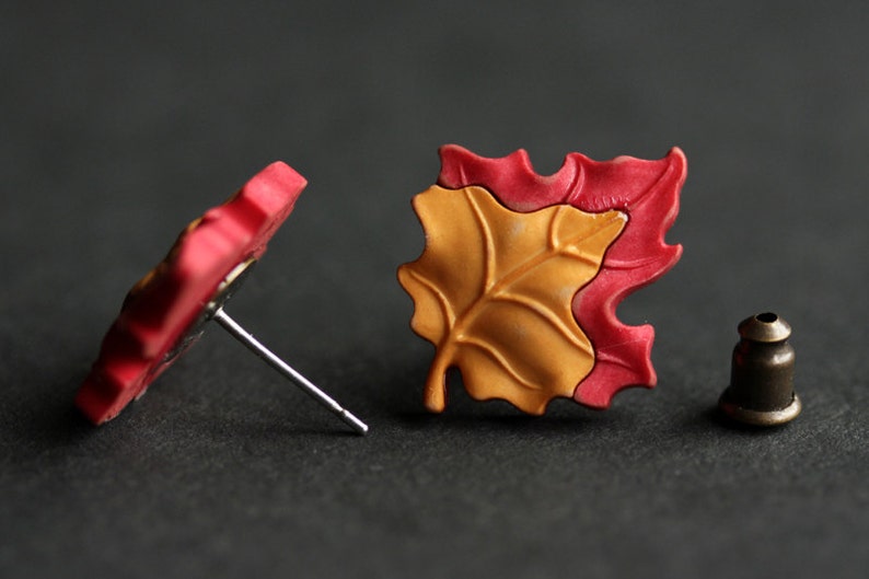 Pu&ograve; includere: Un paio di orecchini a forma di foglia rossa e gialla. Gli orecchini sono realizzati in pasta polimerica e hanno un design semplice ed elegante.