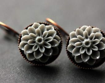 May include: A pair of earrings with a gray flower design. The earrings are made of metal and have a copper finish.