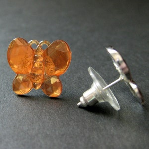 May include: A pair of orange butterfly stud earrings with silver posts and backs.