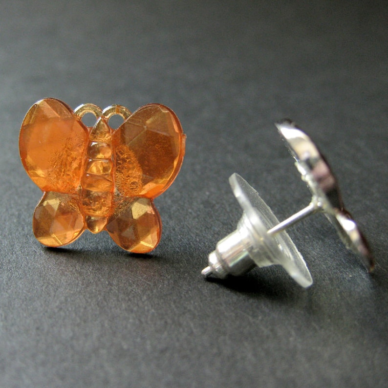 May include: A pair of orange butterfly stud earrings with silver posts and backs.