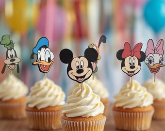 May include: A set of six cupcake toppers featuring illustrated character faces including Mickey Mouse, Minnie Mouse, Donald Duck, Daisy Duck, Goofy, and Pluto, each attached to a thin wooden pick and inserted into individual frosted cupcakes.