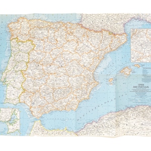 May include: A vintage map of Spain and Portugal, published by the National Geographic Magazine. The map shows the countries' borders, major cities, and geographic features. The map is printed on a light blue background with brown lines and text.