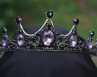 May include: A gothic crown with a black metal frame, decorated with black and lavender gemstones. The crown has an ornate design with curved lines and pointed arches, suitable for cosplay or themed events.