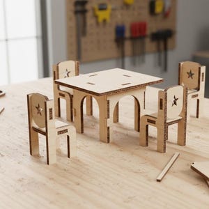 Może przedstawiać: Miniaturowy zestaw drewnianego stołu i krzeseł. Kwadratowy stół ma łukowate nogi, a krzesła mają wycięcia w kształcie gwiazd na oparciach. Zestaw wykonany jest z jasnego drewna i wydaje się być projektem DIY lub rzemieślniczym.