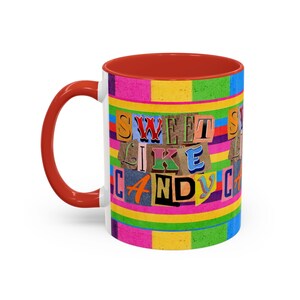 May include: A white ceramic mug with a red interior and handle. The mug features a colorful striped design with the words "SWEET LIKE CANDY" in a collage-style font. The mug is designed for hot or cold beverages.