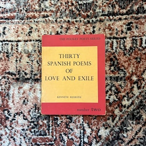 May include: A paperback book titled Thirty Spanish Poems of Love and Exile by Kenneth Rexroth, part of The Pocket Poets Series number two. The cover features a yellow rectangular center with black text on a red background with black borders.