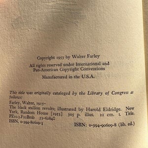 Op de afbeelding: Een open boekpagina met tekst uit "The black stallion revolts" van Walter Farley. De tekst bevat copyrightinformatie, catalogusgegevens van de Library of Congress en ISBN-nummers. Het boek is vervaardigd in de U.S.A.