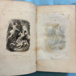 May include: Open book with illustrations from "Paradise Lost" by John Milton. The left page features a detailed engraving of figures with spears and wings. The right page has a faded illustration. The book's pages are aged with visible wear.