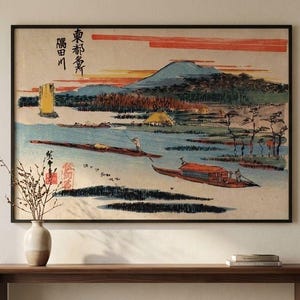 May include: A framed horizontal wall art print featuring a Japanese woodblock style landscape with boats on a river, a distant mountain, and red sunset clouds. The artwork includes black Japanese calligraphy characters in the upper left corner.