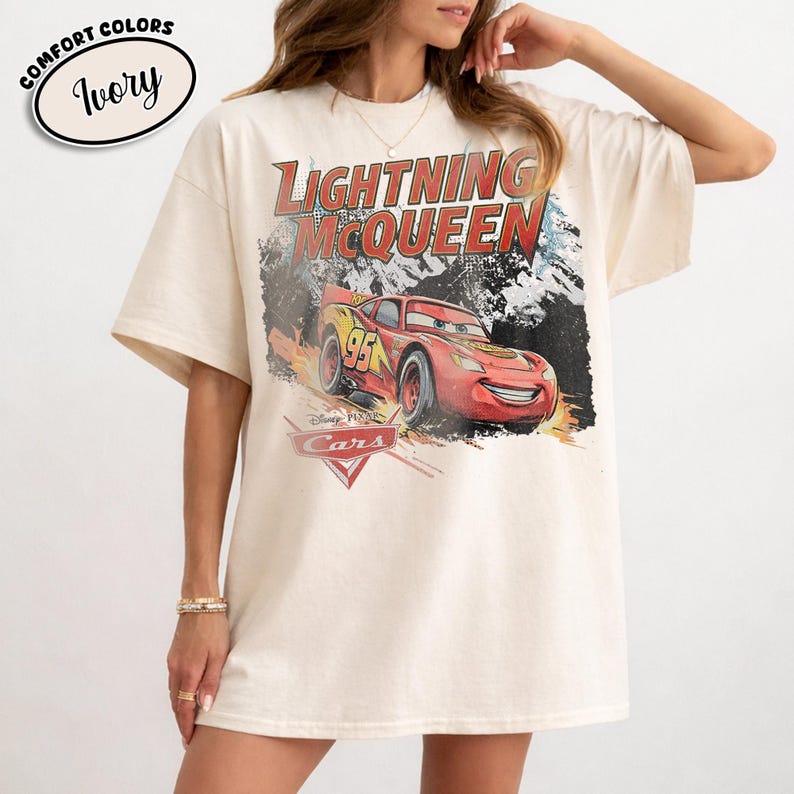 Peut inclure: Un t-shirt ivoire avec une impression graphique du personnage Flash McQueen du film Cars de Disney Pixar. Le motif inclut le texte Lightning McQueen et le logo Cars. Le t-shirt pr&eacute;sente des manches courtes et un col rond.
