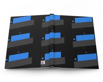 Puede incluir: Diario abierto con una cubierta negra que presenta un patrón geométrico de rectángulos azules y formas grises. El diseño se repite en toda la cubierta. Un pequeño código QR es visible cerca del lomo.