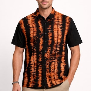 May include: Black and orange tie-dye short-sleeve shirt. The shirt has a button-down front and a classic collar. The tie-dye pattern is vertical, with orange stripes against a black background. The model is wearing khaki pants.
