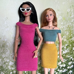 May include: Two fashion dolls standing side by side. The doll on the left has long black hair, white cat-eye sunglasses, and a bright pink off-the-shoulder knit dress. The doll on the right has long auburn hair, a teal off-the-shoulder knit top, and a mustard yellow knit skirt.