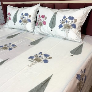 May include: White floral bed set featuring two pillowcases and a fitted sheet. The pillowcases and sheet are adorned with blue, pink, and gray floral bouquets and gray leaf designs. The pillowcases have a decorative diamond pattern border.