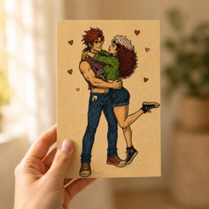 May include: A tan-colored card featuring a colored pencil illustration of two figures embracing. One figure has spiky red hair, a purple sleeveless top, and blue jeans. The other has voluminous brown hair, a green sweater, and blue shorts.