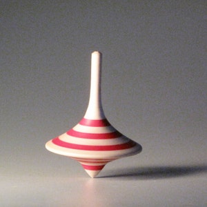 May include: A red and white striped wooden spinning top.