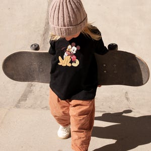May include: A white ceramic mug with a black handle and the text "But First, Coffee" in a bold, black font. The mug is set against a blurred background, highlighting its clean design.