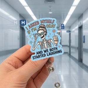 May include: A badge reel with a cartoon skeleton wearing sunglasses and holding a beverage. The text on the badge reads "I asked myself if I'm okay and we both started laughing."
