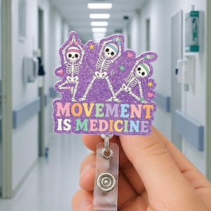 Puede incluir: Un portatarjetas con purpurina morada con tres figuras de esqueleto en posturas de yoga. El texto "MOVEMENT IS MEDICINE" se muestra en letras coloridas. El portatarjetas tiene una correa de plástico transparente y un broche metálico.