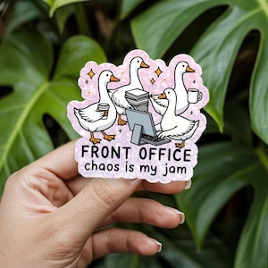 Puede incluir: Una pegatina troquelada con fondo rosa brillante que muestra cuatro gansos blancos en una oficina. Un ganso sostiene un vaso de café, otro escribe en un ordenador, uno está junto a una pila de papeles y otro sostiene una taza. El texto dice: FRONT OFFICE chaos is my jam.