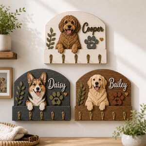 May include: Three wall-mounted wooden key holders featuring sculpted dog figures. One white board with a brown dog named Cooper, one dark gray board with a Corgi named Daisy, and one brown board with a golden dog named Bailey, each with five brass hooks.