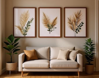 May include: A beige sofa with two light-colored cushions and one tan pillow, flanked by two potted green plants. Above the sofa hang three framed wall art prints, each featuring illustrations of golden palm fronds and green eucalyptus leaves.