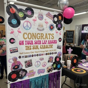 May include: A banner with the text "CONGRATS ON YOUR 50TH LAP AROUND THE SUN, CAROLYN!" features vinyl records, flamingos, and peace signs. The banner is decorated with balloons and fringe, celebrating a birthday.