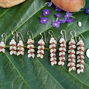May include: Six pairs of shell earrings with gold hooks. The earrings are made of small white and brown shells arranged in a cascading pattern.