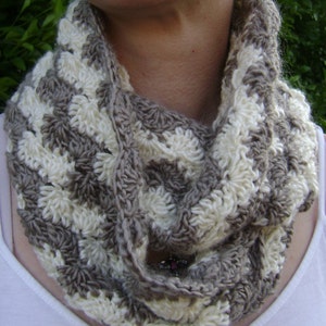 May include: A crocheted infinity scarf in a brown and white striped pattern. The scarf is made with a soft, textured yarn and is perfect for keeping warm in the winter.
