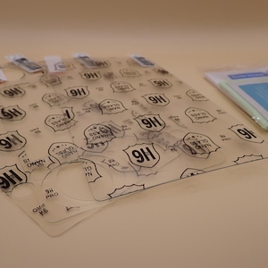 May include: A collection of clear screen protectors with the text "9H Nano Glass Pro" printed on them. The protectors are arranged on a light surface, with a small packet of cleaning supplies visible in the background.