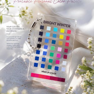 May include: A clear rectangular acrylic keychain labeled BRIGHT WINTER and MAKE UP COLOR, featuring a grid of small colored squares and a horizontal color bar at the bottom. A silver metal ball chain is attached to the top corner of the card.