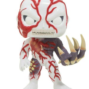 May include: A vinyl figure of a zombie-like character with a white head and red vein-like markings. The figure has a partially exposed skull, a dark purple arm with large yellow claws, and a detailed chest area.