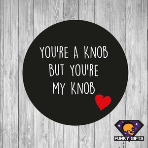 May include: Black and white text on a black circle with a red heart. The text reads "You're a knob but you're my knob".