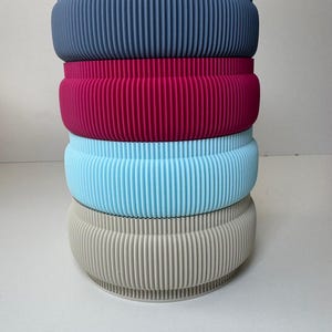 Puede incluir: Un juego de tres tazas de cerámica con un acabado mate moteado. Cada taza presenta un color diferente: azul claro, crema y gris. Las tazas tienen un diseño simple y moderno y un asa cómoda.
