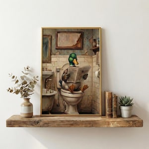 May include: A framed print depicts a duck reading a newspaper while seated on a toilet. The duck has green and brown feathers and is in a vintage bathroom setting. The newspaper's headline is visible.