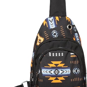 May include: Black sling backpack with a Southwestern-inspired geometric pattern in orange, blue, and white. Features a single adjustable strap, a zippered main compartment, and a smaller front pocket. The bag has a black strap and a black zipper.