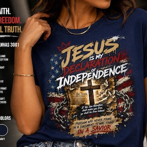 Puede incluir: Una camiseta azul marino con un estampado gráfico de una bandera estadounidense, una cruz de madera y cadenas rotas. El texto dice: Jesus is my declaration of independence, We the People, If the Son therefore shall make you free, ye shall be free indeed, y Freedom was never found in a document. It was found in a Savior.