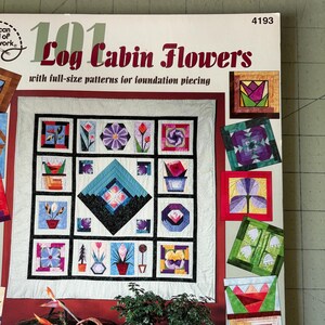 May include: A book cover titled "101 Log Cabin Flowers" by Linda Causee. The cover features a quilt design with various floral patterns and the text "with full-size patterns for foundation piecing". The book is from the American School of Needlework.