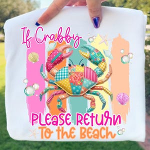 Puede incluir: Camiseta blanca con un diseño de cangrejo colorido. El cangrejo está hecho de tela de retazos y tiene el texto "If Crabby, Please Return To The Beach". El diseño incluye conchas marinas, burbujas y estrellas de mar. También se ven las palabras "CRAB PNG" y "PNG, JPG".